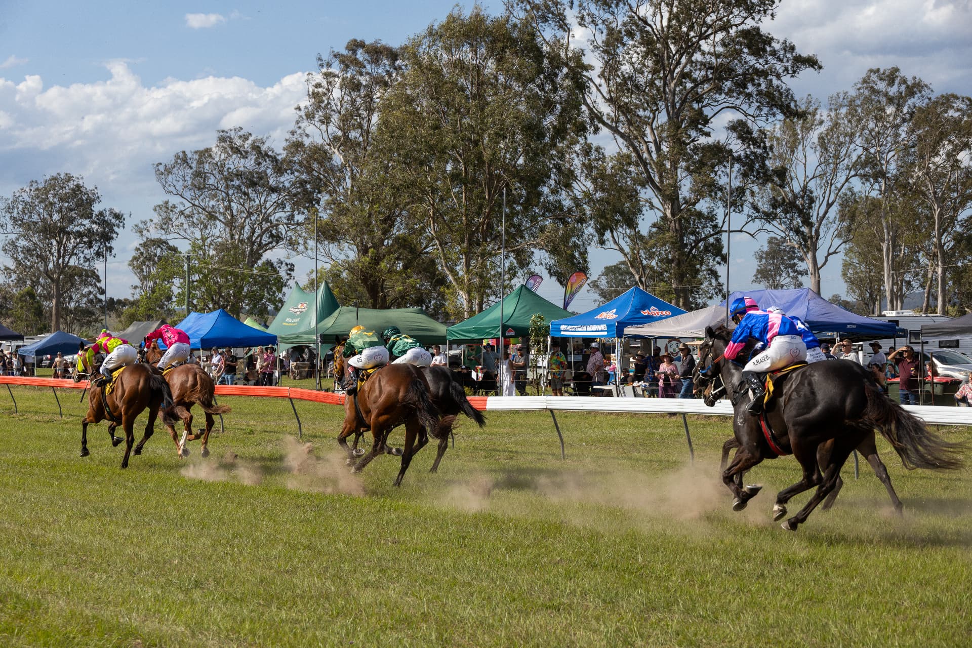 Horses galloping past the trackside tents