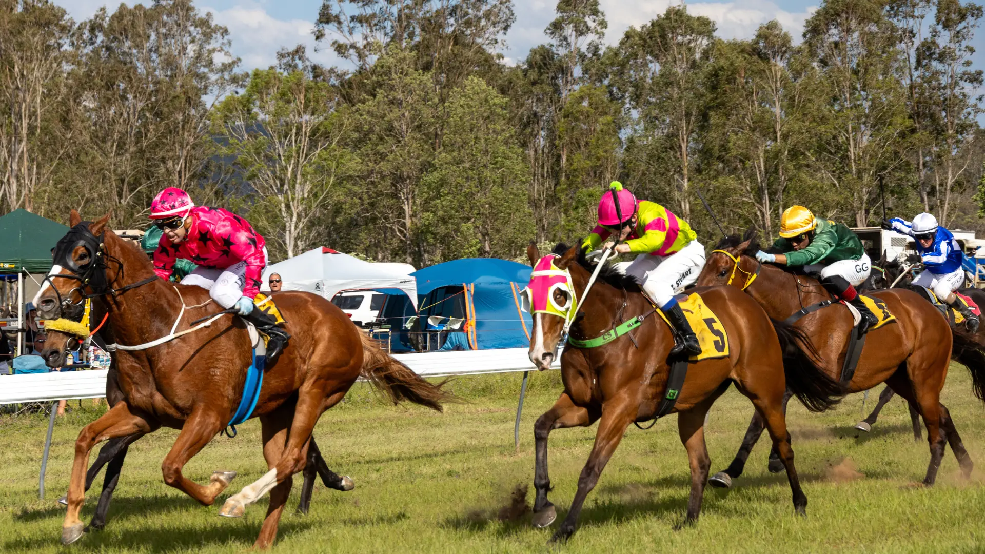 Horses and jockeys racing past the marquees at Tabulam Race Day