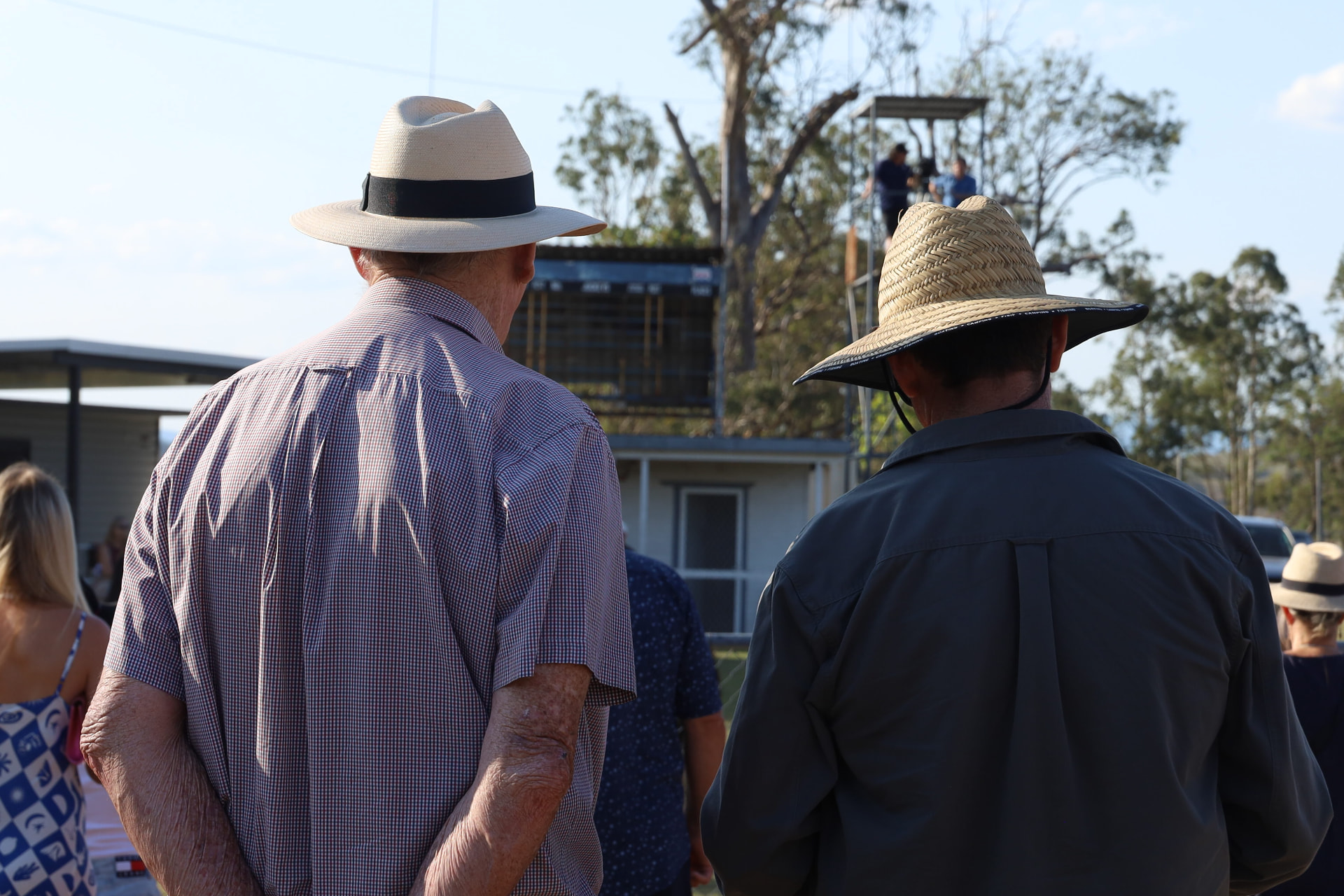 Locals in wide-brim hats watching the track